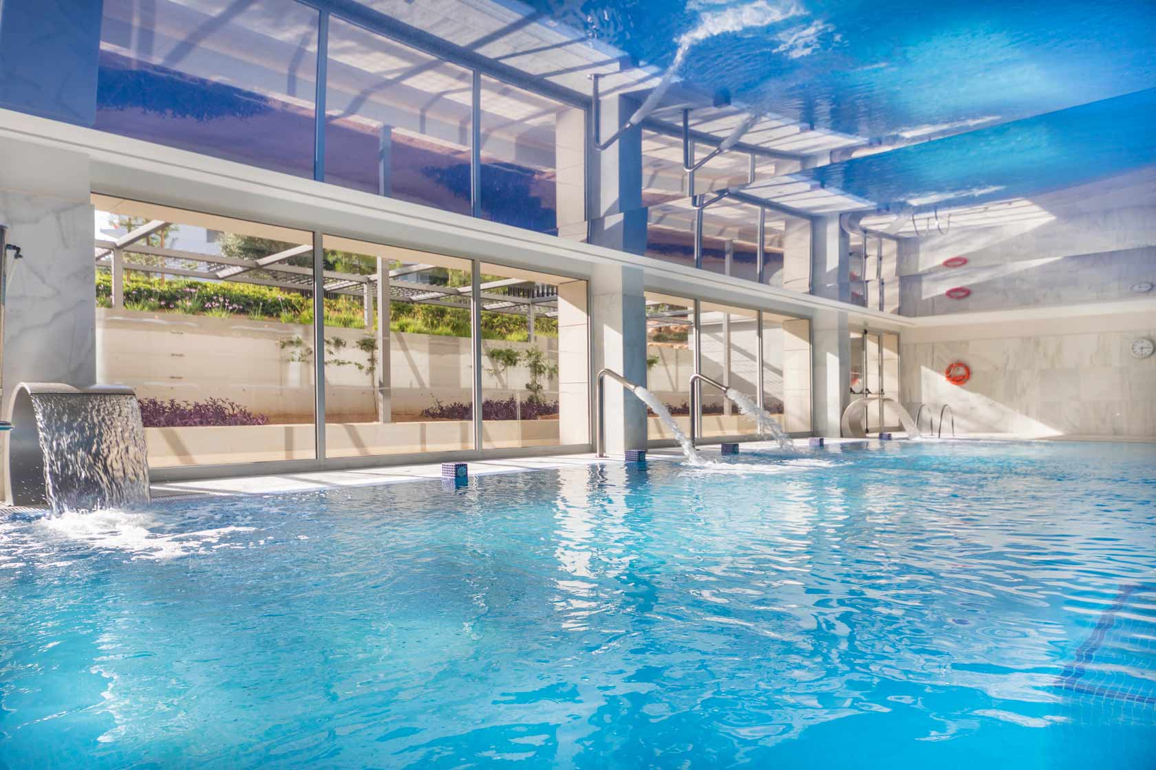 Indoor spa pool with jacuzzi, gooseneck water features and relaxation beds at Mallorca Wellness Spa – Gran Playa de Palma.